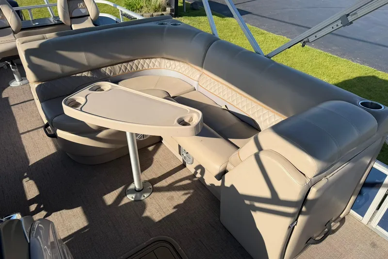 Slide: The Image of 2021 Ranger Reata 223F boat interior with beige seating and table, featuring cup holders. - 17