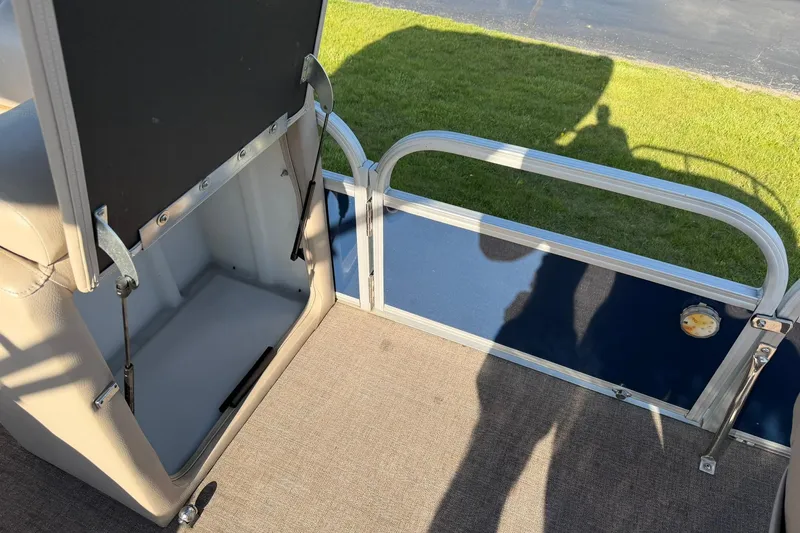 Slide: The Image of 2021 Ranger Reata 223F boat interior with open storage compartment and railing. - 18