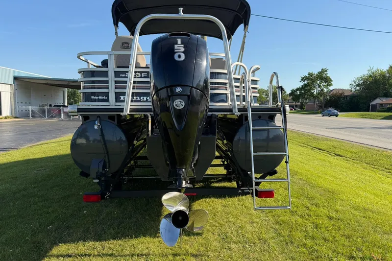 Slide: The Image of 2021 Ranger Reata 223F boat with powerful outboard motor, parked on grass. - 2
