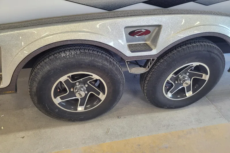 Slide: The Image of 2023 Ranger Z521R trailer wheels with sleek black and silver rims in a garage setting. - 2