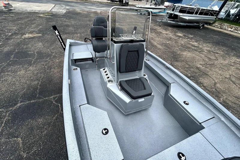 Slide: The Image of 2026 Xpress H20B Bay boat interior with seating and console, parked on pavement. - 29