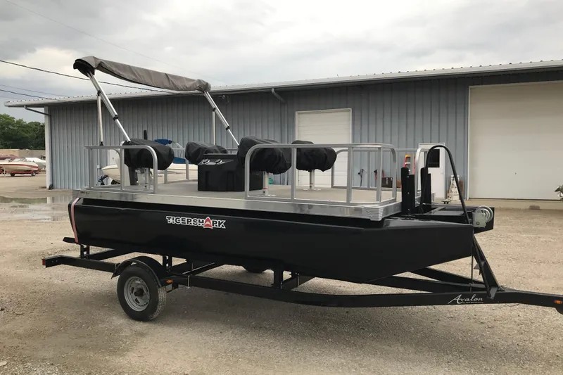Slide: The Image of 2024 Tigershark 700 12' Mini Pontoon on trailer, parked outside a warehouse. - 16