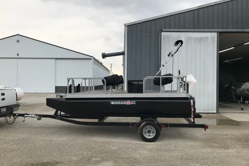 Slide: The Image of 2024 Tigershark 700 12' Mini Pontoon on trailer outside metal building. - 18