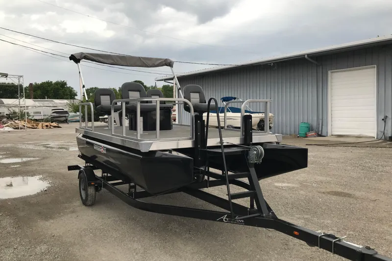 Slide: The Image of 2024 Tigershark 700 12' Mini Pontoon boat on trailer, parked outdoors. - 3