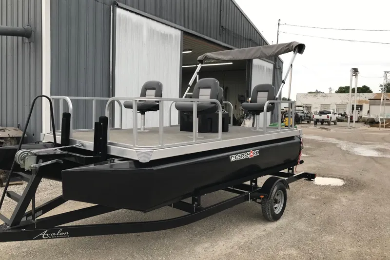 Slide: The Image of 2024 Tigershark 700 12' Mini Pontoon boat on trailer near industrial building. - 4