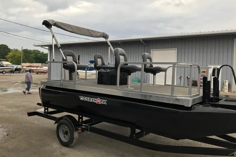 Slide: The Image of 2024 Tigershark 700 12' Mini Pontoon with canopy and seating, parked outdoors. - 5