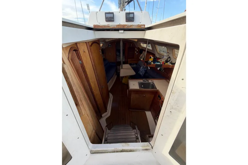 Slide: The Image of Interior view of a 2000 Hunter 310 sailboat, featuring wooden cabinetry and compact kitchen area. - 36