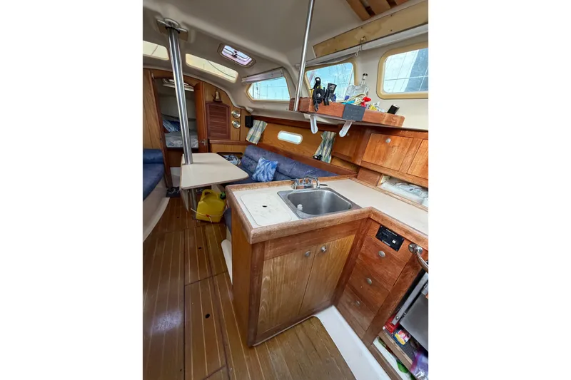 Slide: The Image of Interior of a 2000 Hunter 310 sailboat with wooden cabinetry and compact kitchen area. - 42