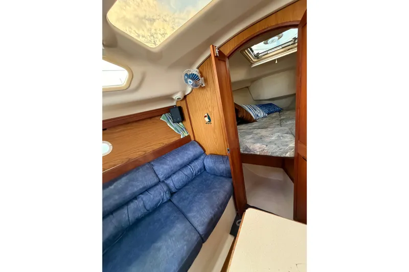 Slide: The Image of Interior of 2000 Hunter 310 sailboat with blue seating and cozy sleeping area. - 46