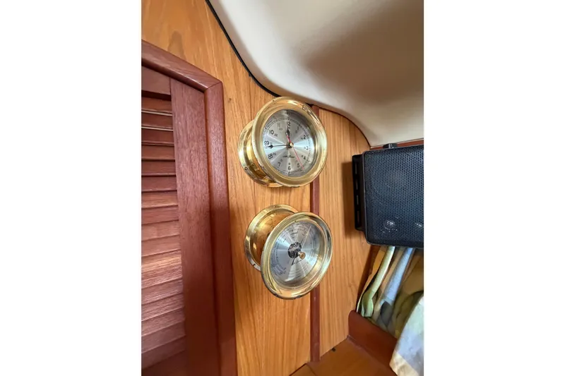 Slide: The Image of Brass nautical instruments on a wooden panel inside a 2000 Hunter 310 sailboat. - 49