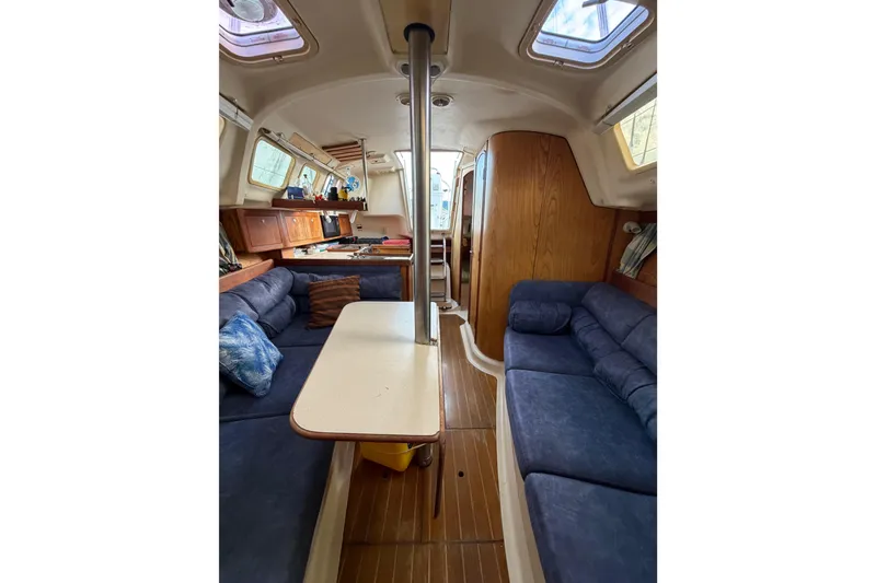 Slide: The Image of Interior of a 2000 Hunter 310 sailboat with blue seating and wooden accents. - 53