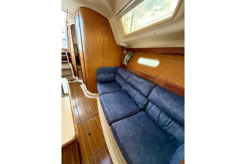 Slide: The Image of Interior of 2000 Hunter 310 sailboat with blue cushioned seating and wooden paneling. - 54