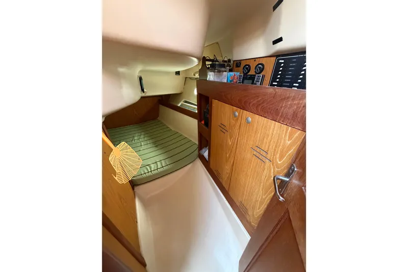 Slide: The Image of Interior cabin of a 2000 Hunter 310 sailboat with wood cabinetry and a cushioned berth. - 58