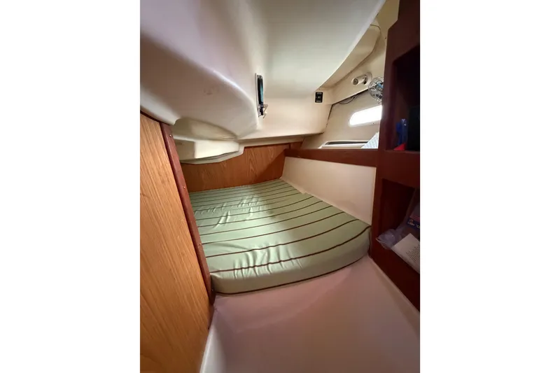 Slide: The Image of Cozy cabin interior of 2000 Hunter 310 sailboat with striped mattress and wooden accents. - 61