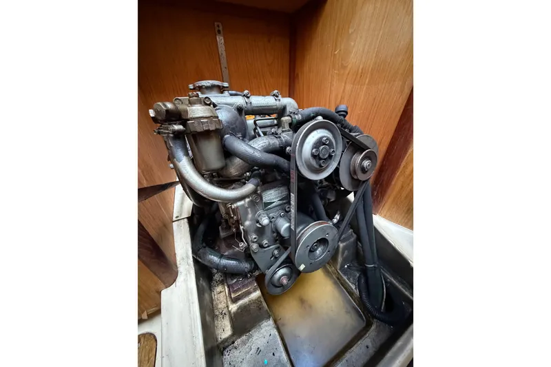 Slide: The Image of Engine of a 2000 Hunter 310 sailboat, showcasing belts and hoses in a wooden compartment. - 68