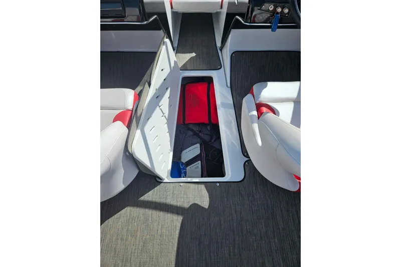 Slide: The Image of 2021 Glastron GTS 205 boat interior with open storage compartment between seats. - 12
