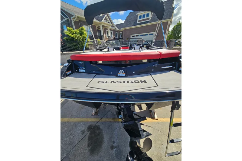 Slide: The Image of 2021 Glastron GTS 205 boat, rear view, parked in driveway, showcasing sleek design. - 17
