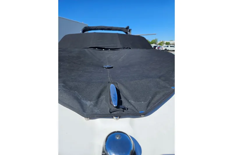 Slide: The Image of 2021 Glastron GTS 205 boat with black cover under clear blue sky. - 18