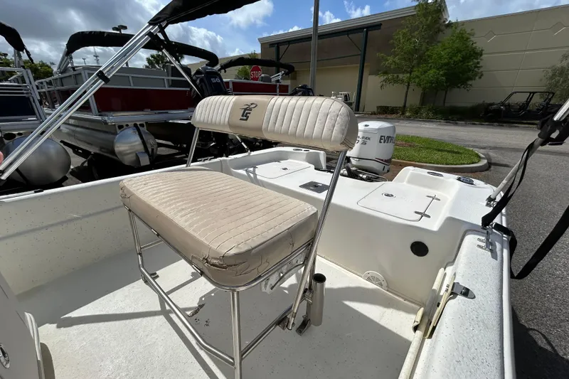 Slide: The Image of 2015 Carolina Skiff JVX18CC boat interior with seating and motor, parked outdoors. - 9