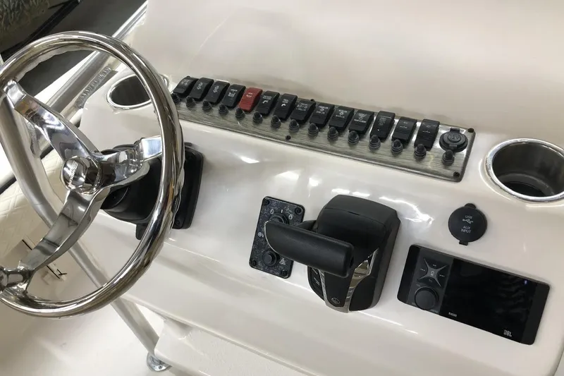 Slide: The Image of Control panel of 2025 Carolina Skiff 22 Ultra Elite boat with steering wheel and switches. - 9