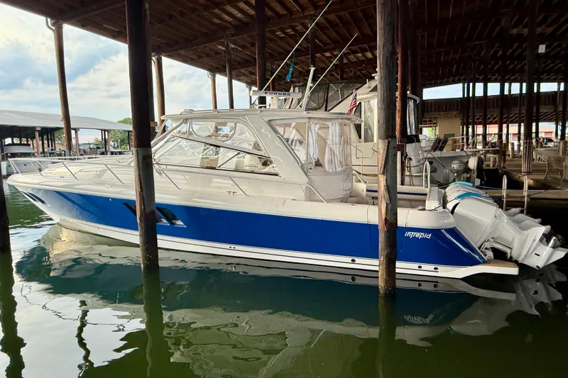 The Image of 2017 Intrepid 475 Sport Yacht docked under a wooden shelter. - 1