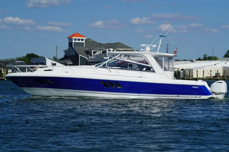Slide: The Image of 2017 Intrepid 475 Sport Yacht cruising on a sunny day near coastal homes. - 12