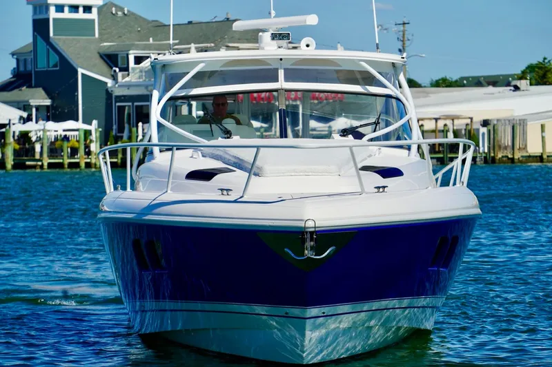 Slide: The Image of 2017 Intrepid 475 Sport Yacht cruising on water near coastal buildings. - 2