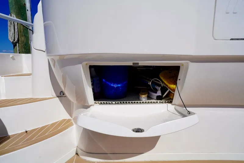 Slide: The Image of Storage compartment on a 2017 Intrepid 475 Sport Yacht, featuring cleaning supplies and accessories. - 27