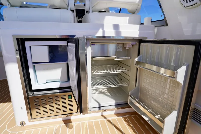 Slide: The Image of 2017 Intrepid 475 Sport Yacht interior with open fridge and freezer on deck. - 30