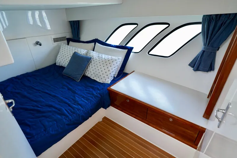 Slide: The Image of Luxurious cabin interior of 2017 Intrepid 475 Sport Yacht with blue bedding and wooden accents. - 63