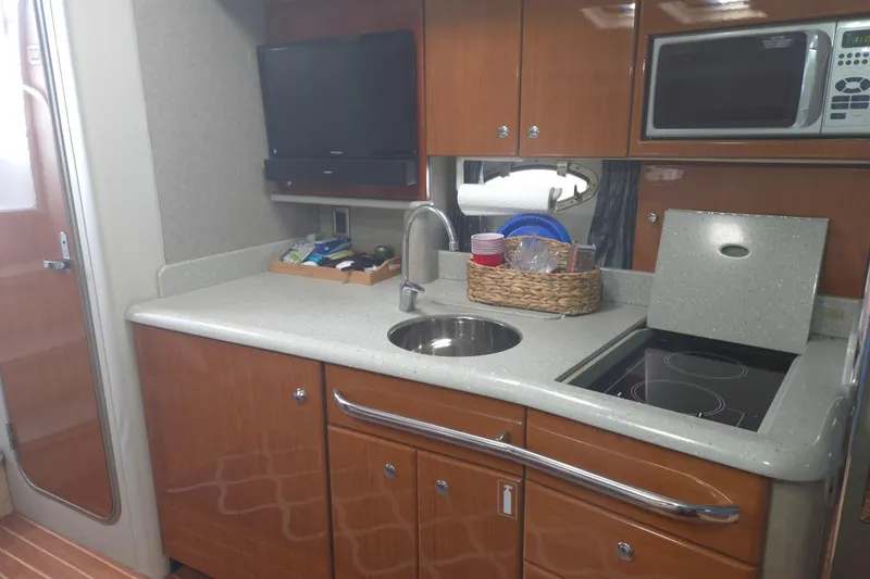 Slide: The Image of 2005 Formula 37 Performance Cruiser kitchen with sink, stove, microwave, and TV. - 14