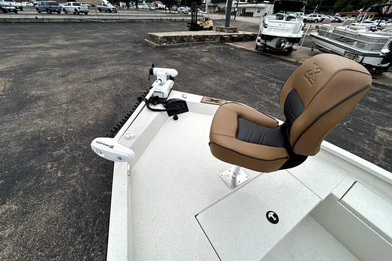 Slide: The Image of 2026 Xpress H20B Bay boat with tan seat and trolling motor in a parking lot. - 12