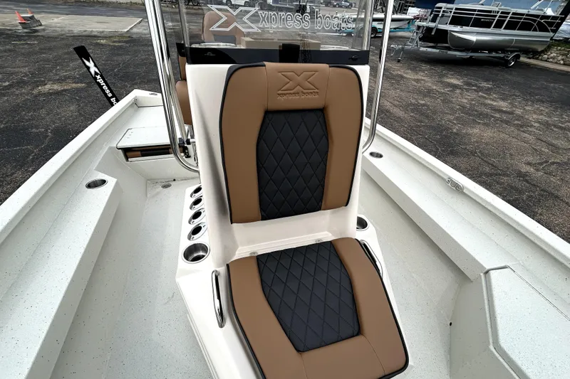 Slide: The Image of 2026 Xpress H20B Bay boat with tan and black seating, docked outdoors. - 22