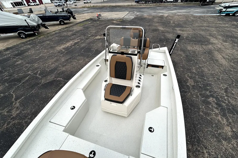 Slide: The Image of 2026 Xpress H20B Bay boat with tan and black seating, parked on asphalt. - 26