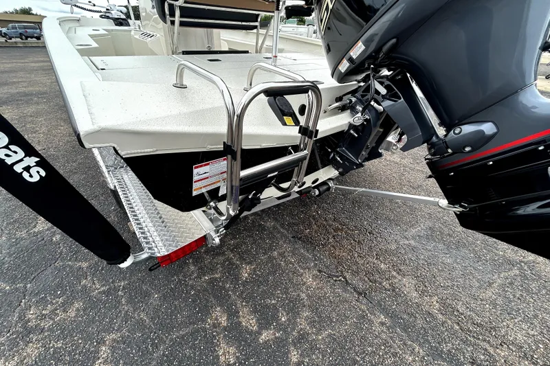 Slide: The Image of 2026 Xpress H20B Bay boat rear view with motor and ladder on pavement. - 6