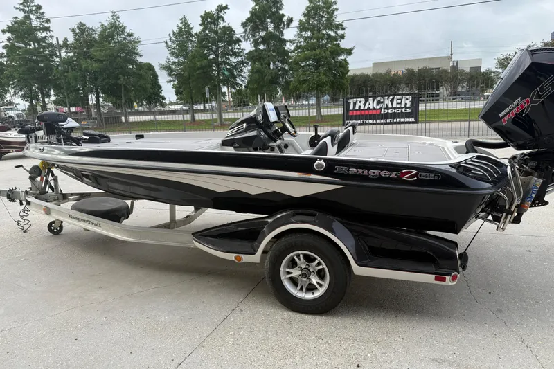 Slide: The Image of 2016 Ranger Z518C Intracoastal boat on trailer, parked outdoors with trees in background. - 7