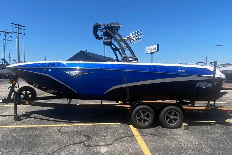 The Image of 2021 Tigé Z3 boat in blue on a trailer, parked in a lot under clear skies. - 1