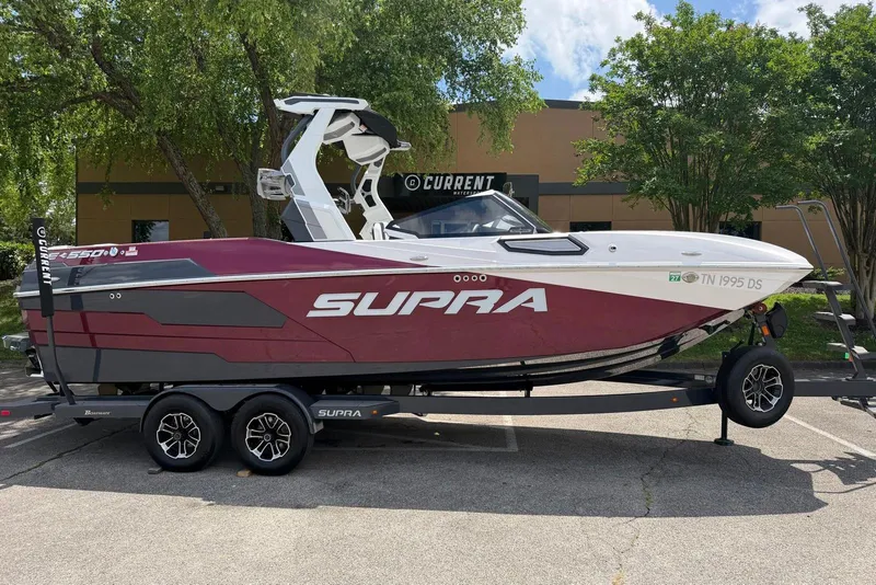 The Image of 2024 Supra SE 550 boat on trailer, parked outdoors, featuring sleek design and vibrant colors. - 0