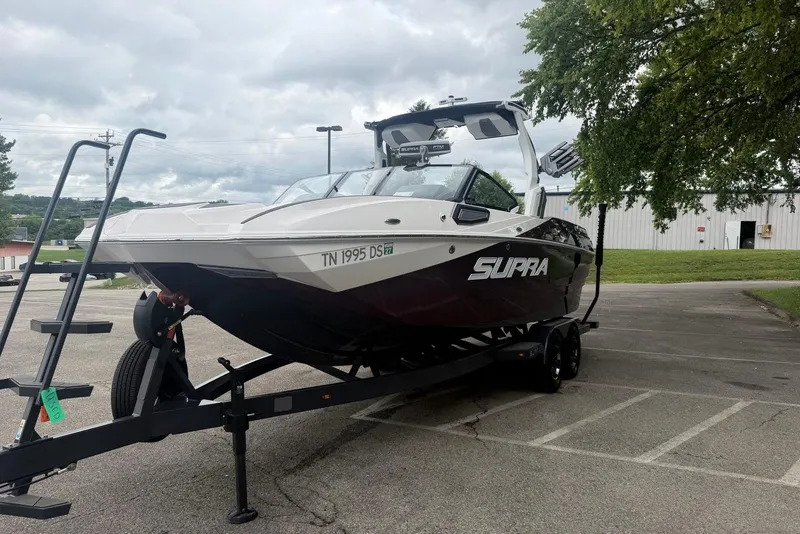 Slide: The Image of 2024 Supra SE 550 boat on trailer in parking lot, overcast sky. - 1
