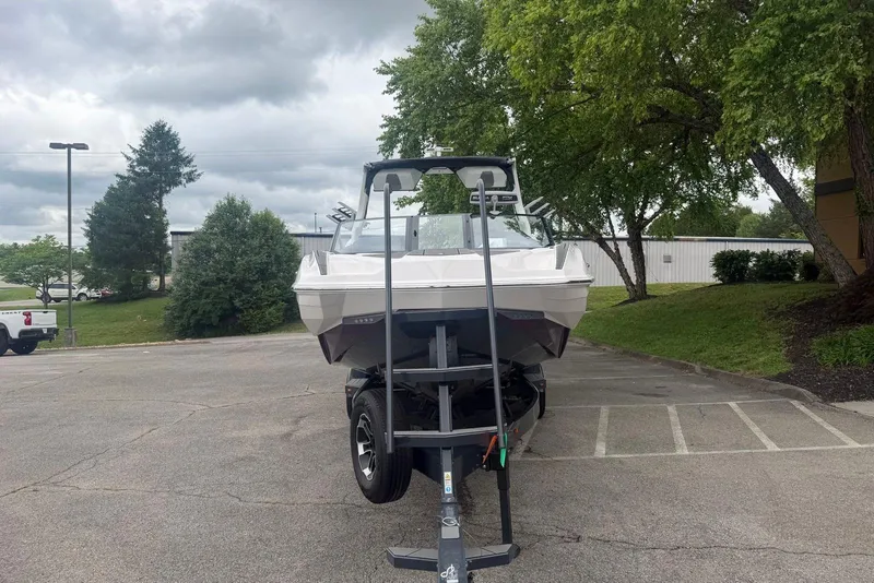 Slide: The Image of 2024 Supra SE 550 boat on trailer in parking lot, surrounded by trees. - 3