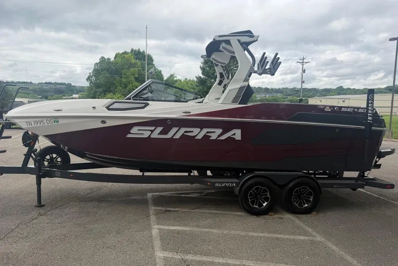 Slide: The Image of 2024 Supra SE 550 boat on trailer, parked outdoors under cloudy sky. - 5