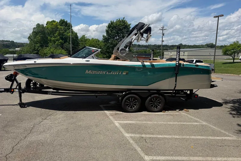 Slide: The Image of 2020 MasterCraft XT25 boat on trailer in parking lot, under clear sky. - 4