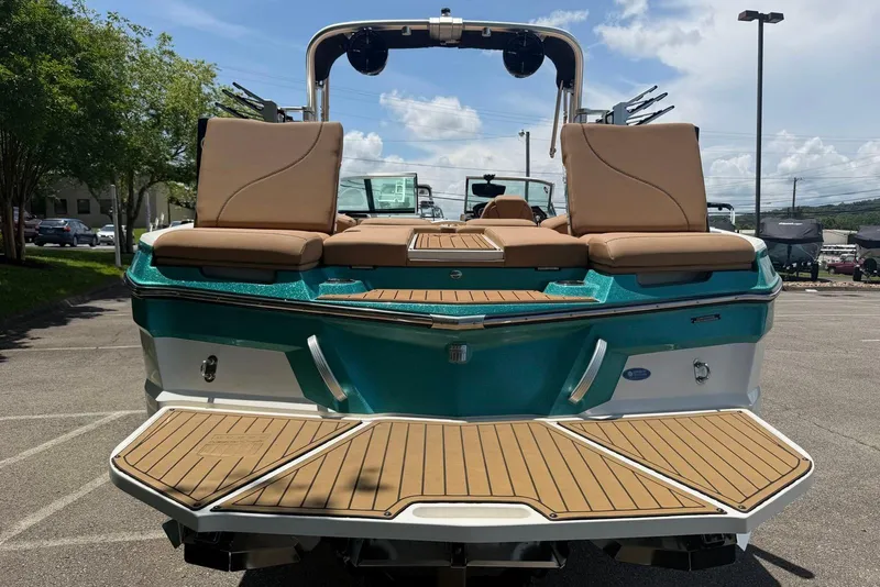 Slide: The Image of 2020 MasterCraft XT25 boat with tan seating and teal accents, parked outdoors. - 6