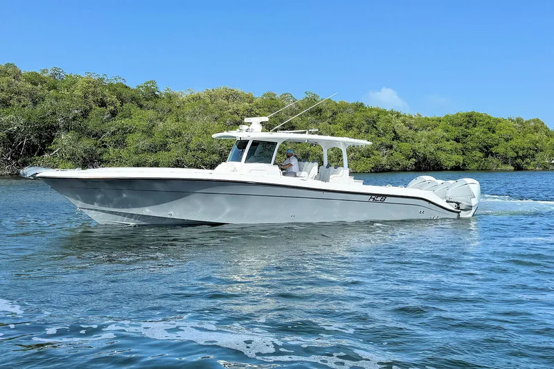 Slide: The Image of 2020 HCB 42 Siesta boat cruising on a sunny day near lush greenery. - 4