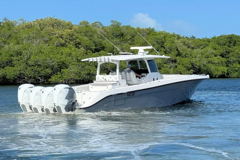 Slide: The Image of 2020 HCB 42 Siesta boat cruising on water with lush greenery background. - 5