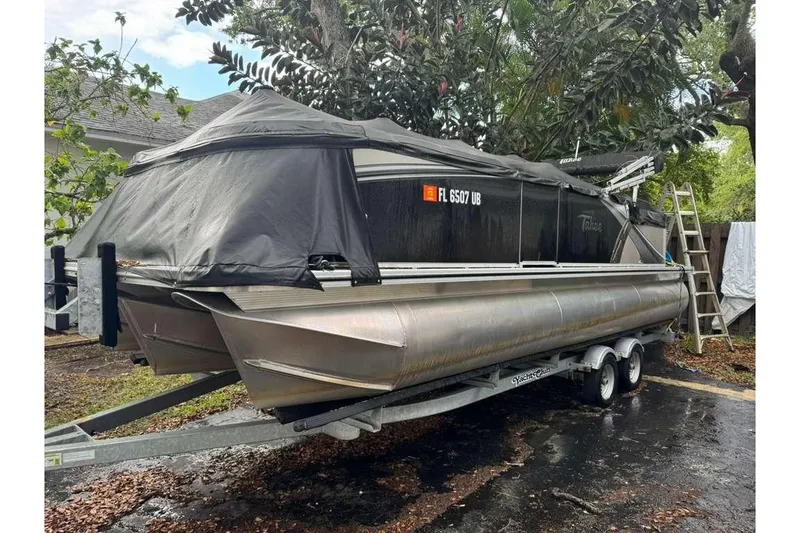 Slide: The Image of 2023 Tahoe Pontoon LTZ 2385 Quad Lounge on trailer, covered, parked outdoors. - 9