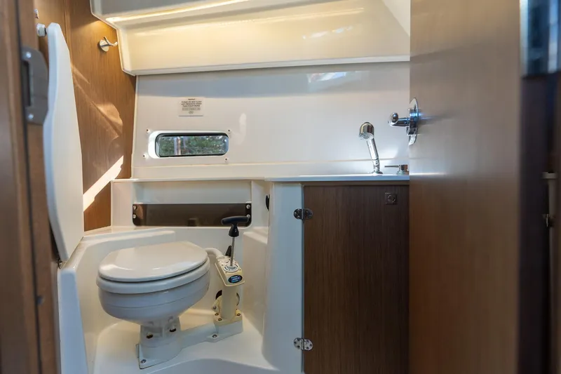 Slide: The Image of 2021 Beneteau Antares 9 bathroom interior with toilet, sink, and wooden cabinetry. - 11