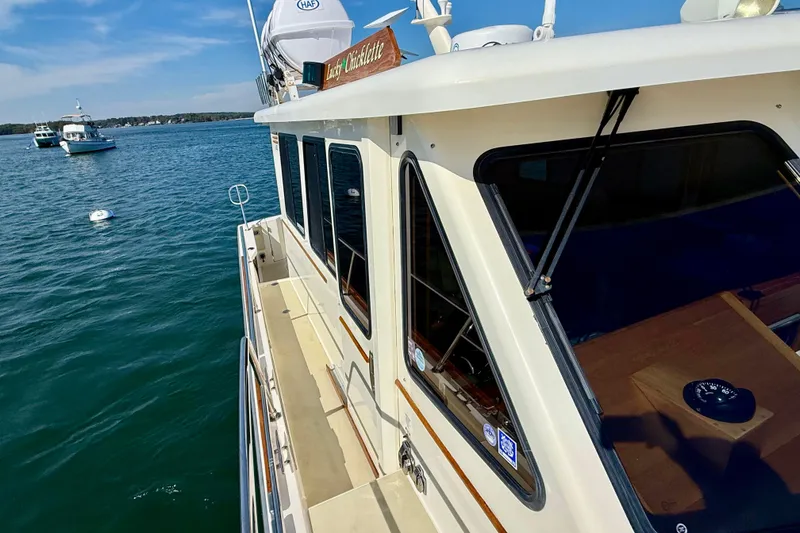 Slide: The Image of 2006 Sabre 42 Sedan yacht on calm water, showcasing sleek design and spacious deck. - 16