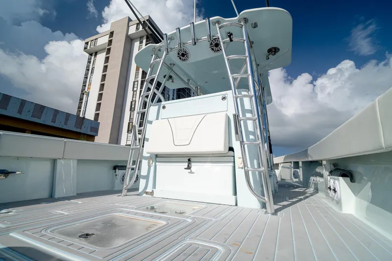 Slide: The Image of 2023 SeaVee 390Z boat deck with ladder, against a cloudy sky and building backdrop. - 28