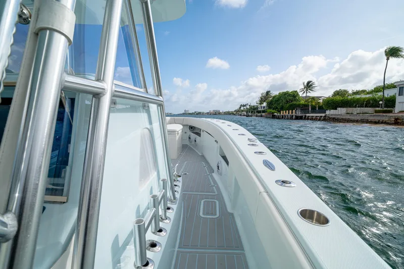 Slide: The Image of 2023 SeaVee 390Z boat cruising along a scenic waterfront under a clear blue sky. - 45